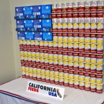 An American flag made of soup cans and boxes of macaroni cheese, entitled "California Feeds the USA"