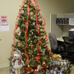 A Christmas tree with a lot of canned food under it