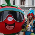 A girl poses with the California Fresh tomato mascot